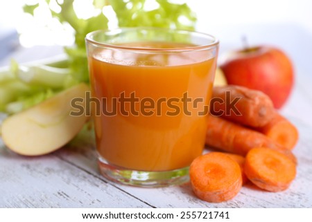 Glass of juice with apple and carrot on wooden table close up