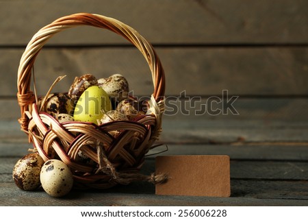 Bird eggs in wicker basket on wooden background