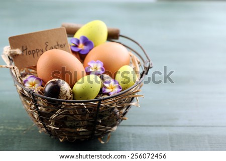 Bird eggs in wicker basket with decorative flowers on color wooden background