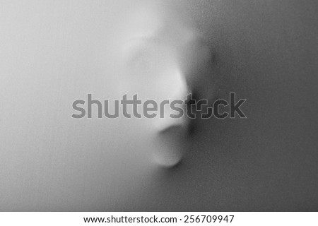 Screaming human face pressing through fabric as horror background