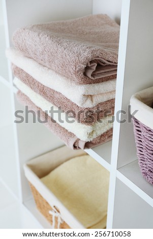 Pile of towels with wicker basket on shelves of rack background