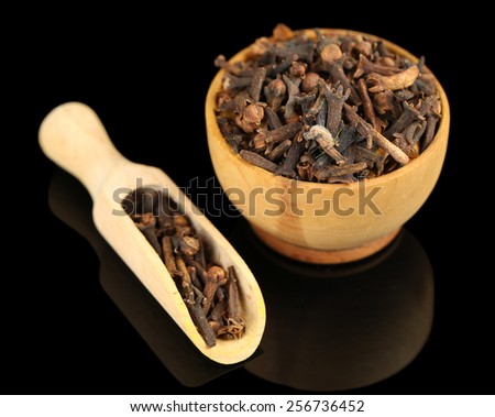 Clove spice in wooden bowl, isolated on black