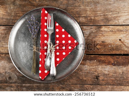 Silverware tied with rope on metal tray with colorful napkin and dried flower on wooden planks background