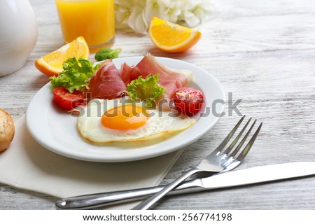 Bacon and eggs on color wooden table background.