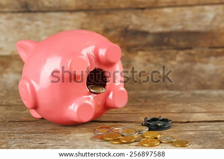 Opened piggy bank with coins on old wooden table