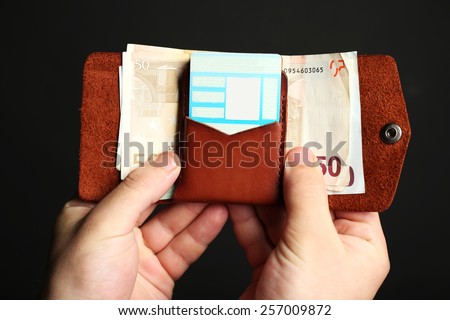 Man holding hand made leather wallet with money and cards on black background