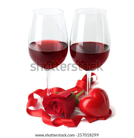 Composition with red wine in glasses, red rose, ribbon and decorative hearts isolated on white