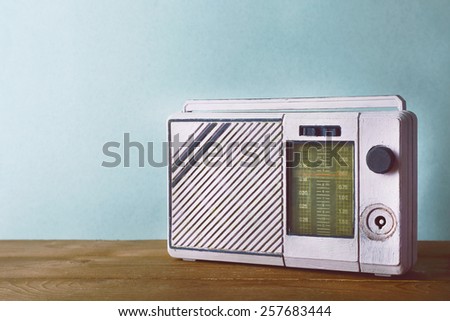 Retro radio on wooden table on light colorful background