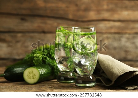 Glasses with fresh organic cucumber water on wooden table