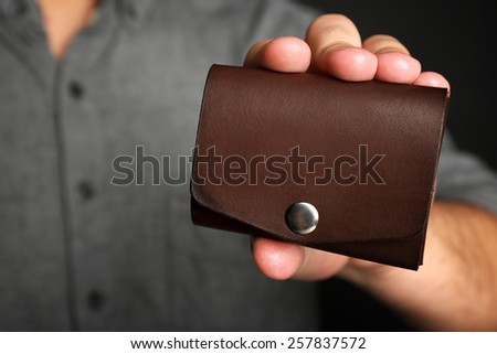 Man holding hand made leather wallet on black background