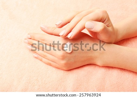 Woman caring hands with cream on fabric background