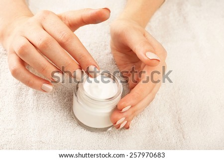 Female hand with cream on terry towel background