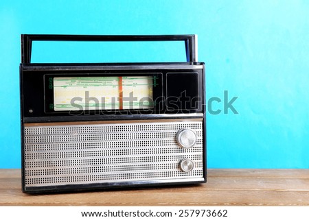 Retro radio on wooden table on blue background