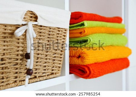 Colorful towels with wicker basket on shelf of rack background