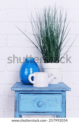 Interior design with plant, decorative vase and watering pot on tabletop on white brick wall background