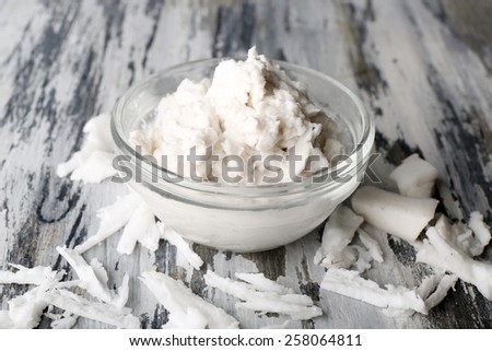 Coconut oil in bowl and coconut flakes on wooden background