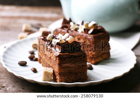Tasty piece of chocolate cake with lump sugar and coffee beans on wooden table background