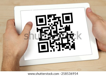 Hand holding tablet with QR code on screen