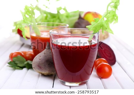 Glasses of beet juice with vegetables on wooden table closeup