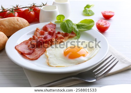 Bacon and eggs on color wooden table background