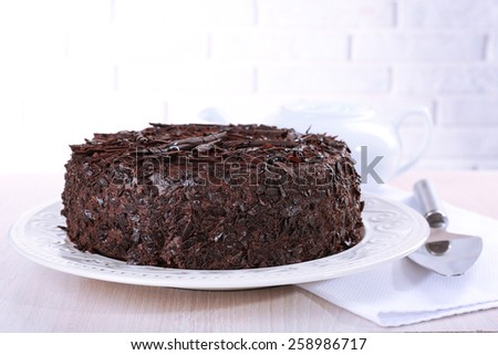 Tasty chocolate cake on table on brick wall background