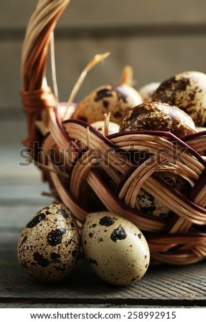 Bird eggs in wicker basket on wooden background