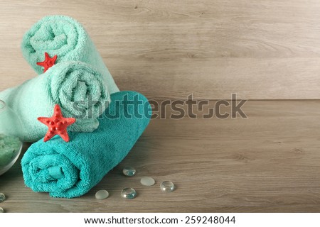 Beautiful towels with sea stars and decorative stones on wooden background