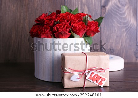 Bouquet of red roses in textile box with present on wooden background