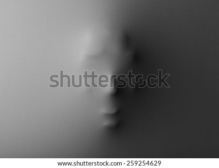 Human face pressing through fabric as horror background