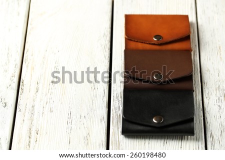 Three hand made leather man wallets on white wooden background