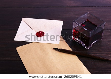 Envelope with pen and ink on wooden background