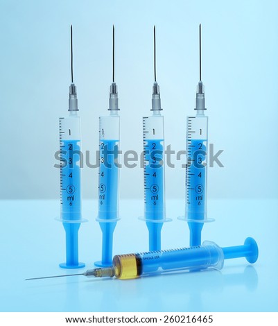 Syringes with medicine on blue background