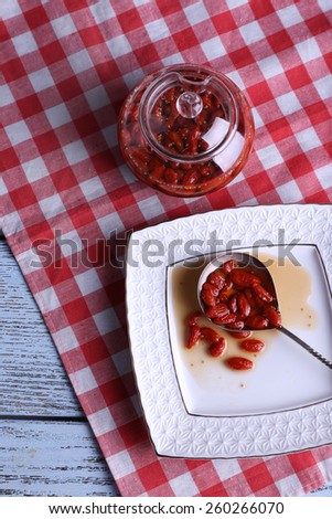 Goji berry jam in spoon on plate with jar on table close up