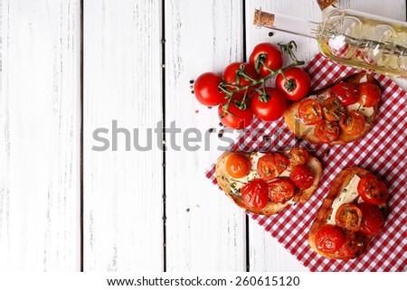 Slices of white toasted bread with butter and canned tomatoes on wooden background