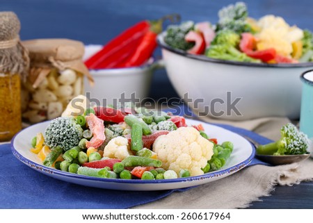 Frozen vegetables on plate on napkin, on wooden table background