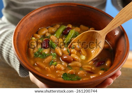 Female hands with beans soup in bowl, close-up