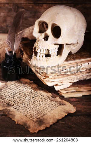 Still life with human skull, retro book and quill on wooden table, closeup