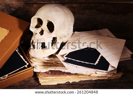 Still life with human skull and retro book on wooden table, closeup