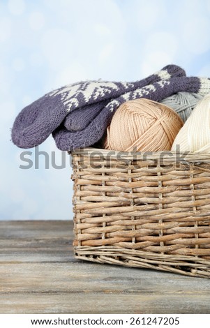 Knitting yarn and mittens in basket, on light background