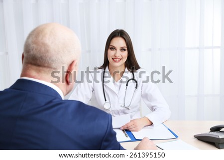 Young female doctor receiving patient in her office on white curtain background