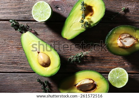Sliced avocado with herb and lime on wooden background