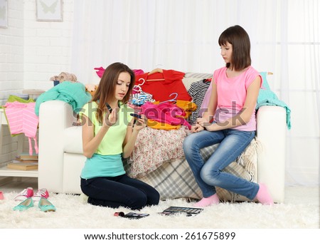 Two girls with clothes and decorative cosmetics at home
