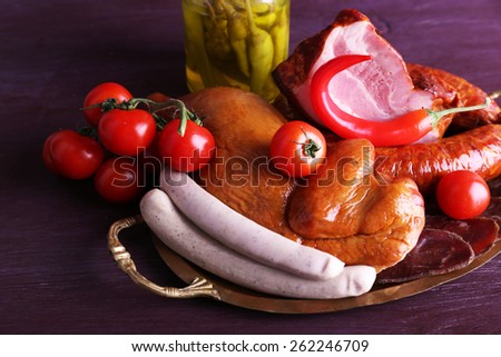 Assortment of deli meats on metal tray on color wooden background