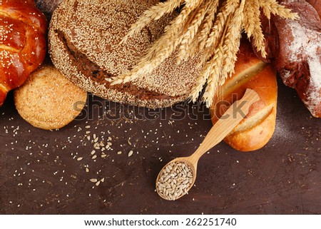 Different bread with ears and sunflower seeds on wooden background
