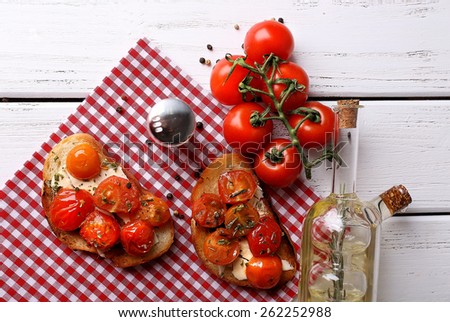 Slices of white toasted bread with butter and canned tomatoes on wooden background
