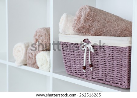 Rolled towels with wicker basket on shelf of rack background