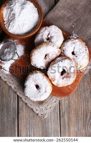 Delicious donuts with icing and powdered sugar on wooden background