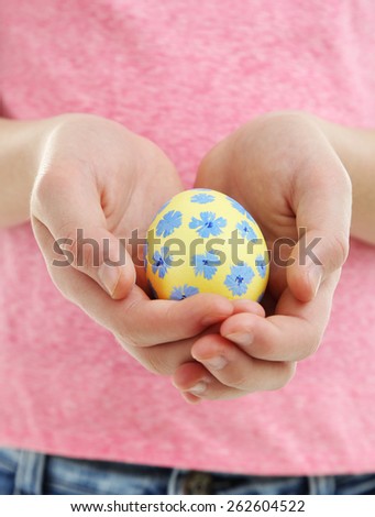 Girl holding painted egg in her hands, close-up