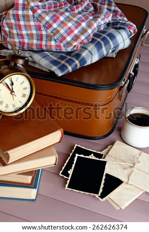 Vintage suitcase with clothes and books om wooden background