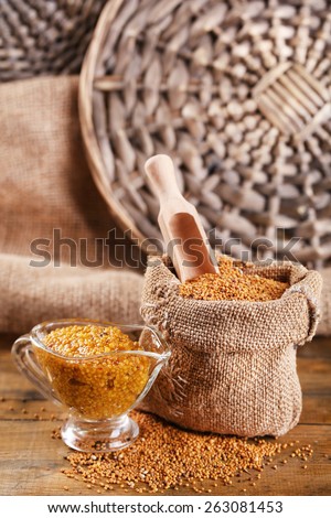 Mustard seeds in bag and sauce in sauce-boat on  wooden background